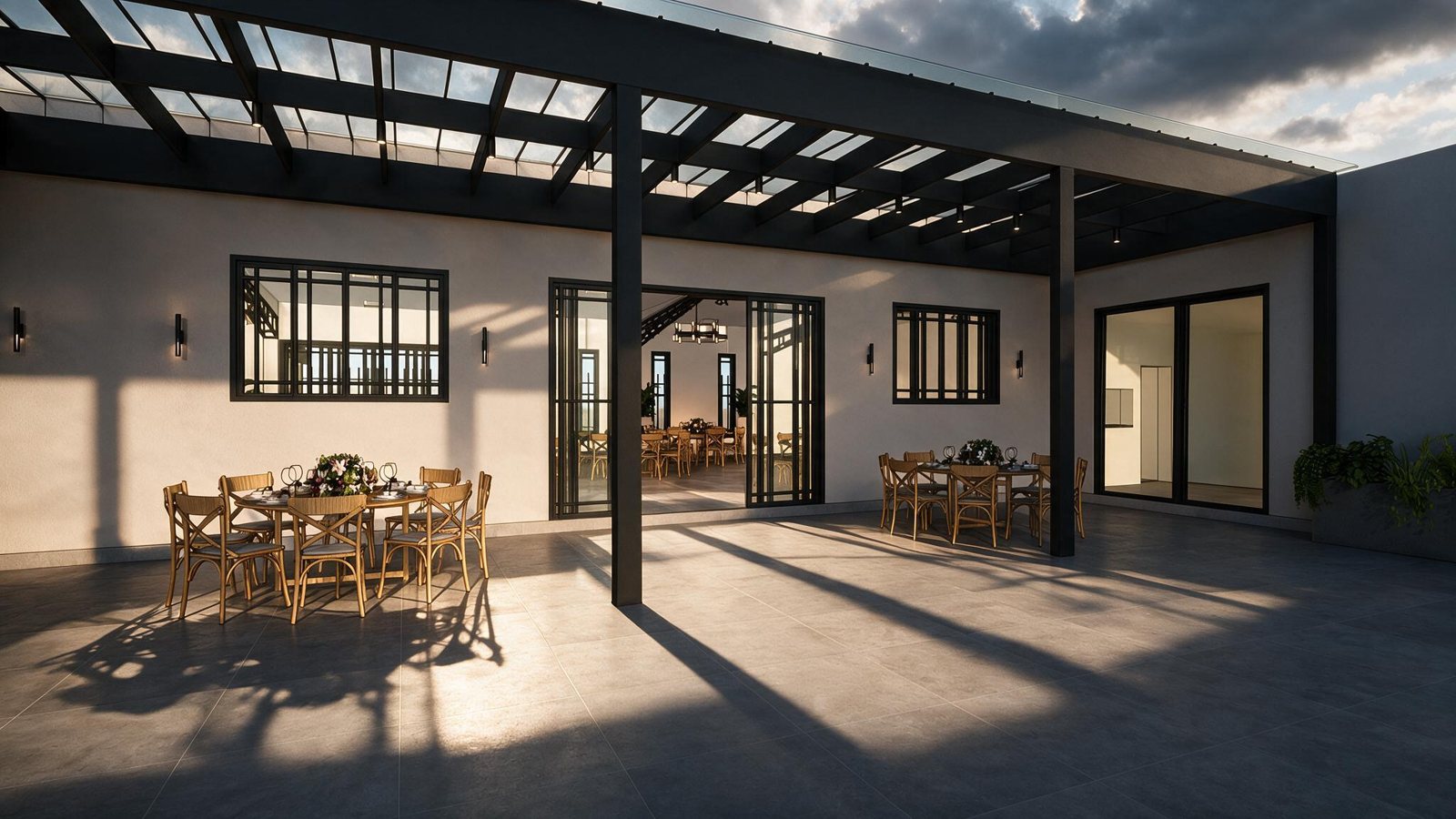 Área exterior bajo la pérgola con mesas, luz del atardecer y puertas hacia el salón