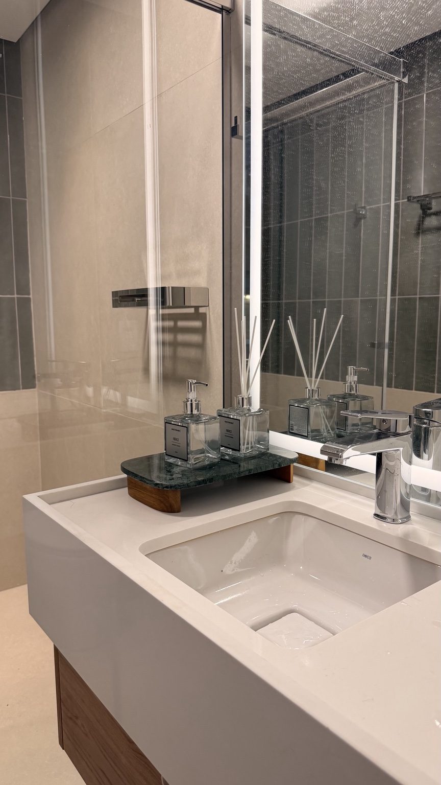 Detalle del mueble con encimera blanca, pileta bajo encimera y bandeja de mármol verde