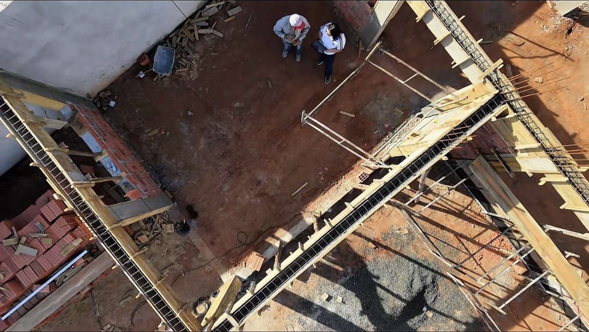 Vista cenital del interior de la obra con encofrados de vigas armadas, ladrillos y visita técnica