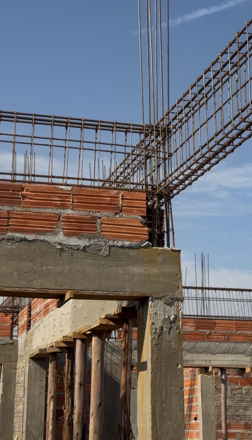 Estructura de hormigón con vigas, armaduras y alvenaría de ladrillo cerámico, apuntalada con puntales de madera