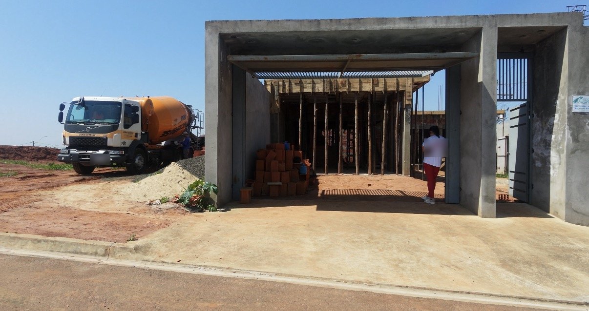 Frente de la obra con la estructura de hormigón, puntales bajo la losa y camión hormigonera en la calle